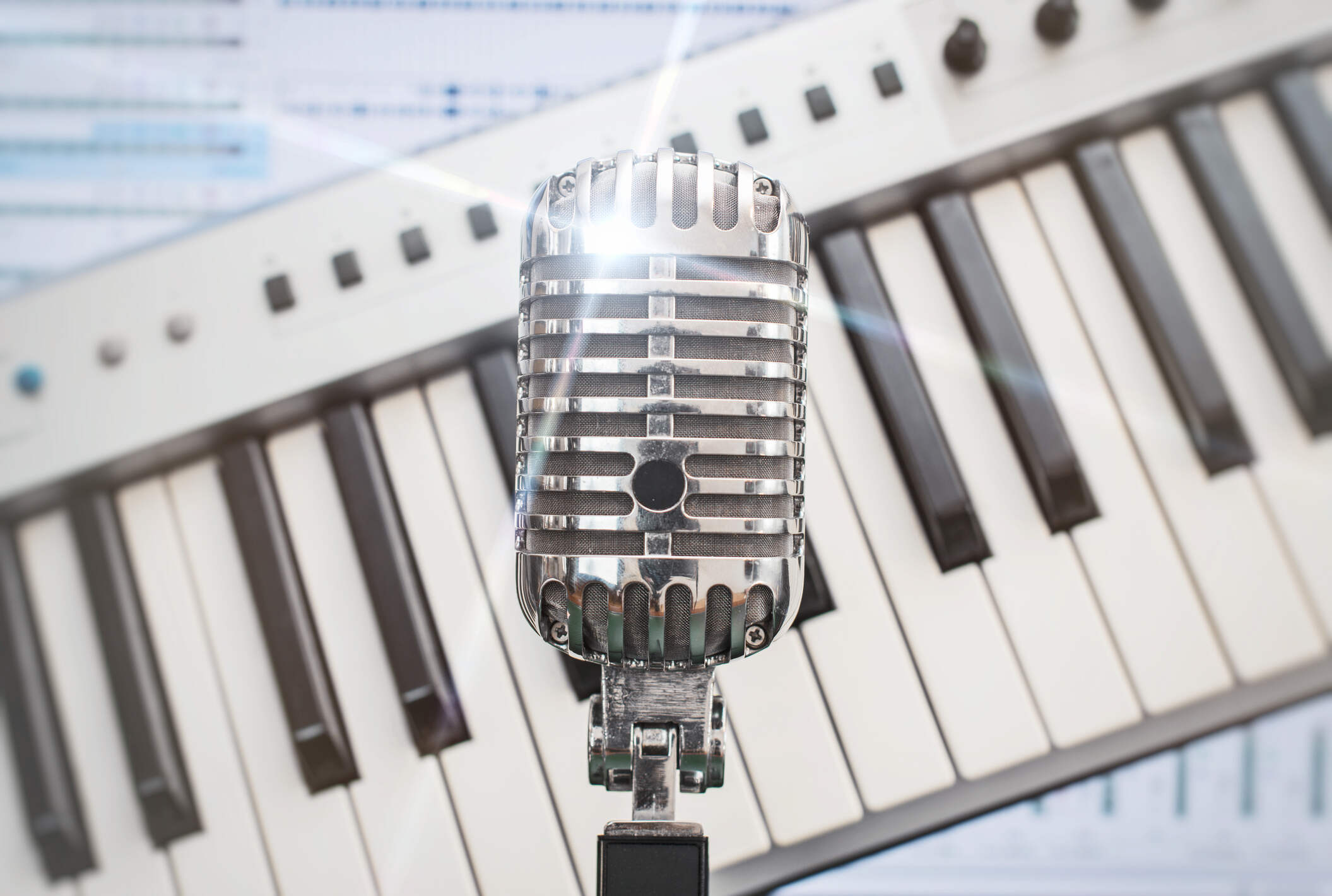 Retro microphone over piano and recording software background.